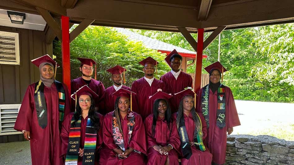 Adults in maroon graduation caps and gowns pose for a group photo.
